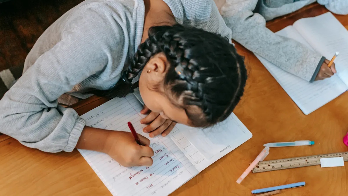 Collaborative writing features: comments, assignments, and version history — Children writing in copybooks at table