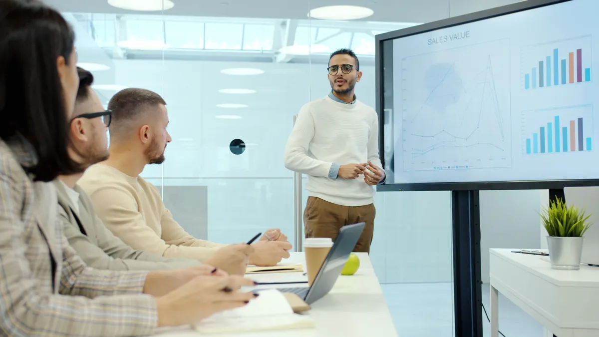 Content brief software: what it is and how teams use it — Diverse Team Meeting with Presentation in Office