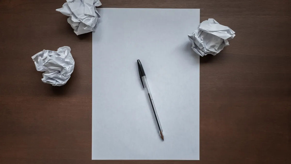 SaaS for writers: the main software categories explained — Flat lay with blank writing sheet, pen and crumpled paper bal