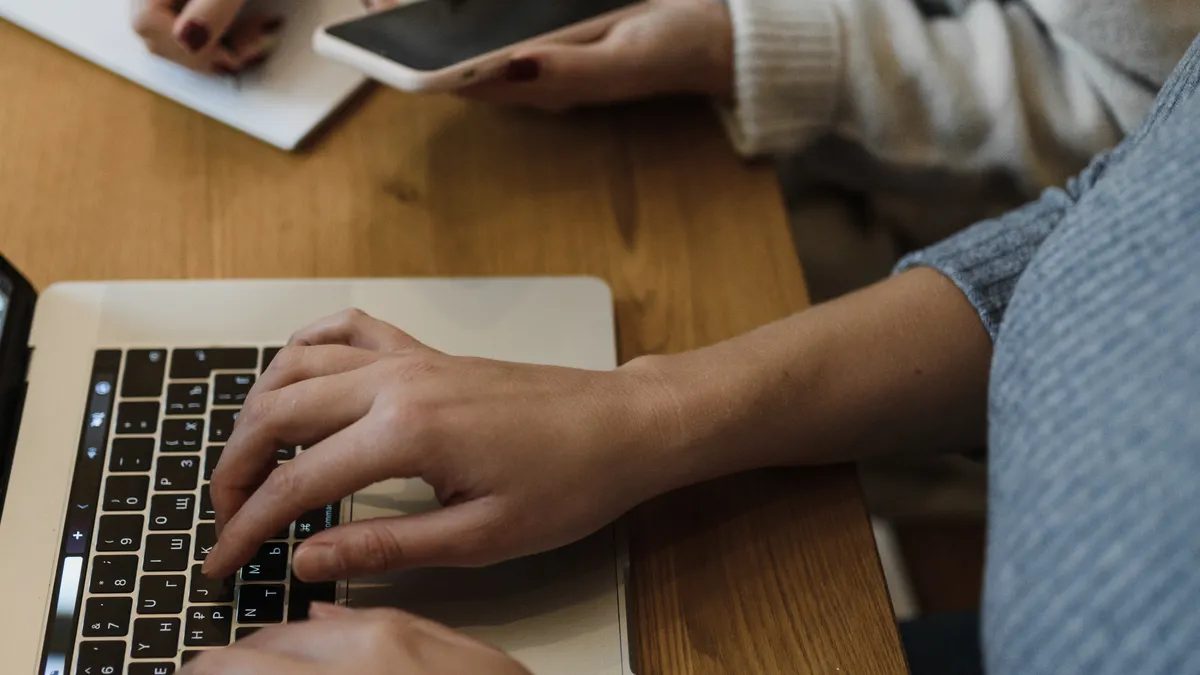 SaaS for writers: the main software categories explained — Person in Gray Sweater Typing on a Laptop Beside a Person Wri