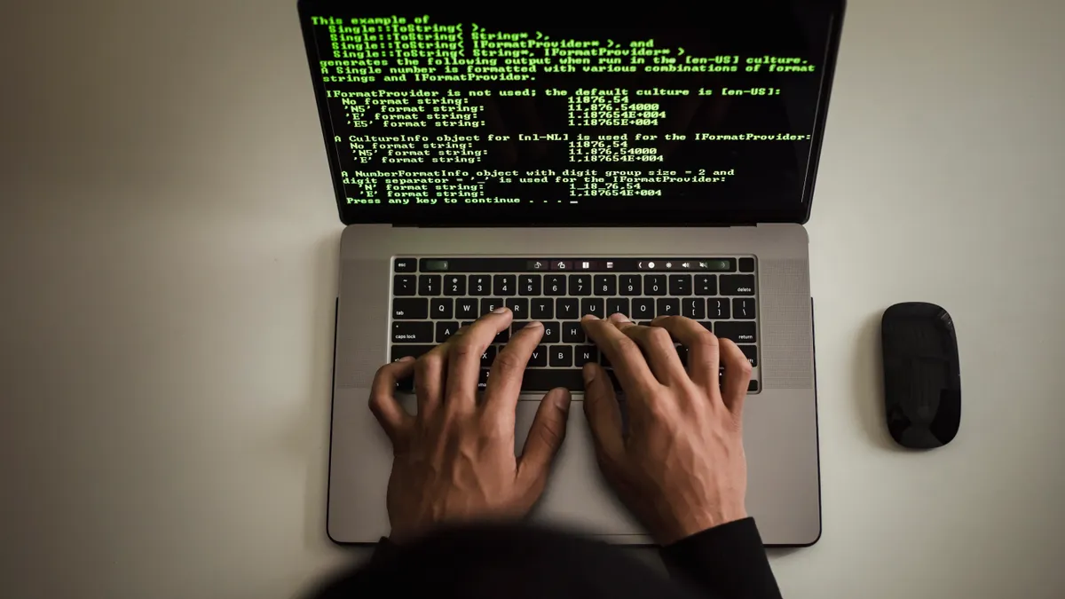 Writing software security and permissions for teams — Crop faceless developer working on software code on laptop